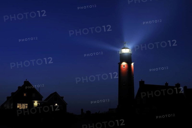 Houses and light beams from lantern of the Cocksdorp lighthouse Eierland at night