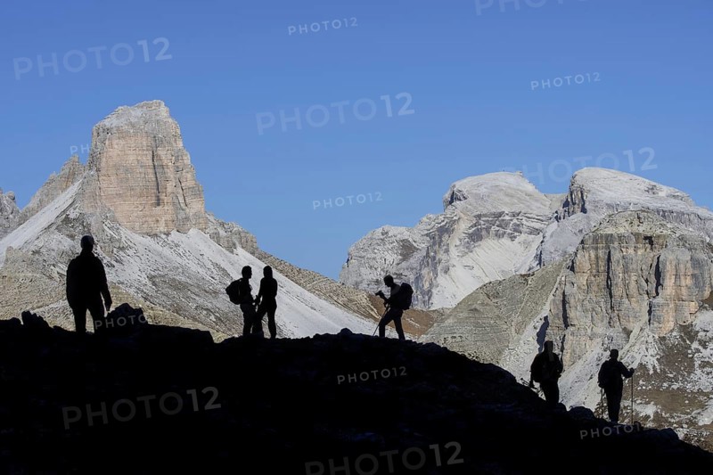 Mountain walkers silhouetted against Torre dei Scarperi
