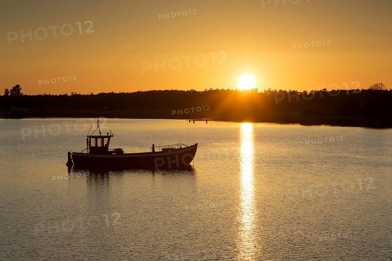 Fishing boat silhouetted against sunset