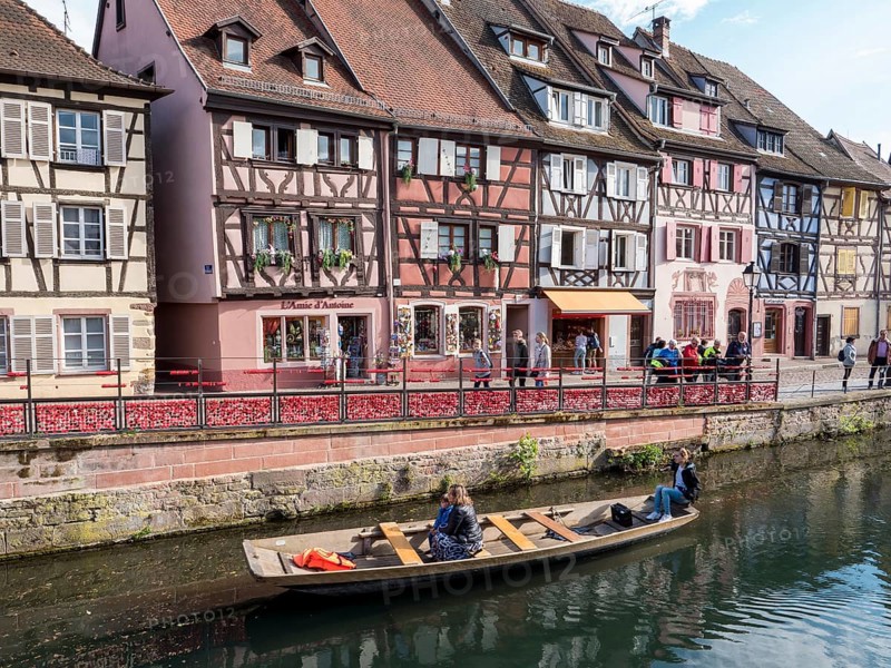 Half-timbered houses along the course of the Lauch with boat and tourists in the district of La Petite Venise