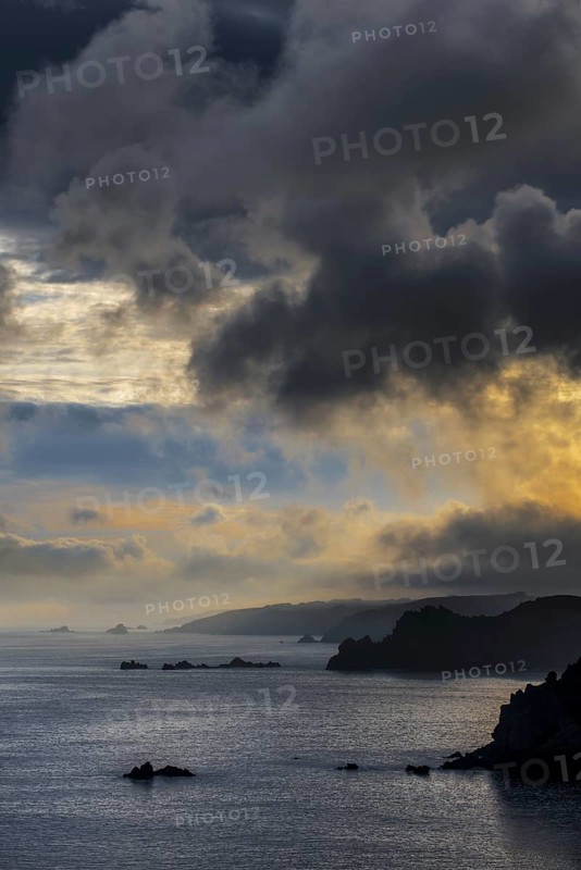 Sea cliffs at the Pointe de Penharn at sunrise with storm clouds