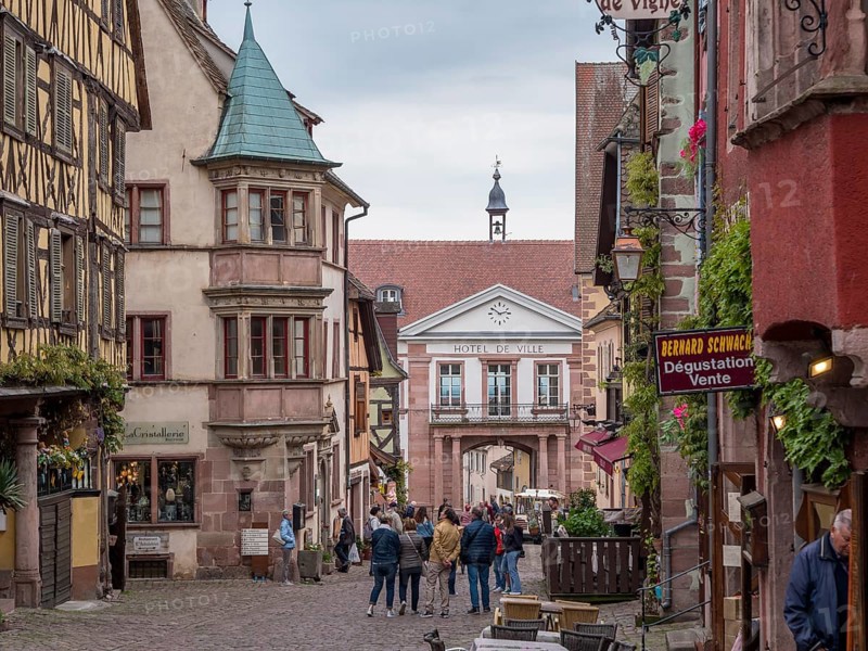 Colourful half-timbered houses and tourists in the Rue du General de Gaulle and in the background town hall Hotel de Ville