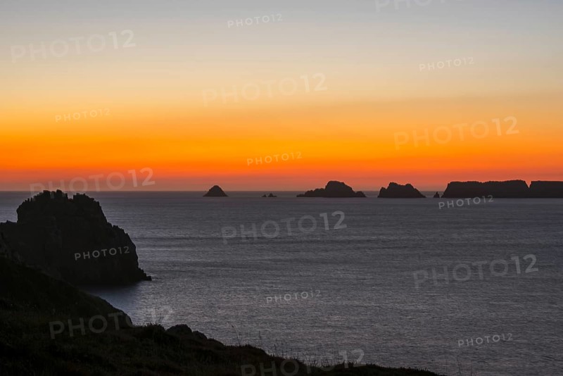 Sea cliffs at the Pointe de Pen-Hir and Les Tas de Pois sea stacks silhouetted against sunset on the Crozon Peninsula