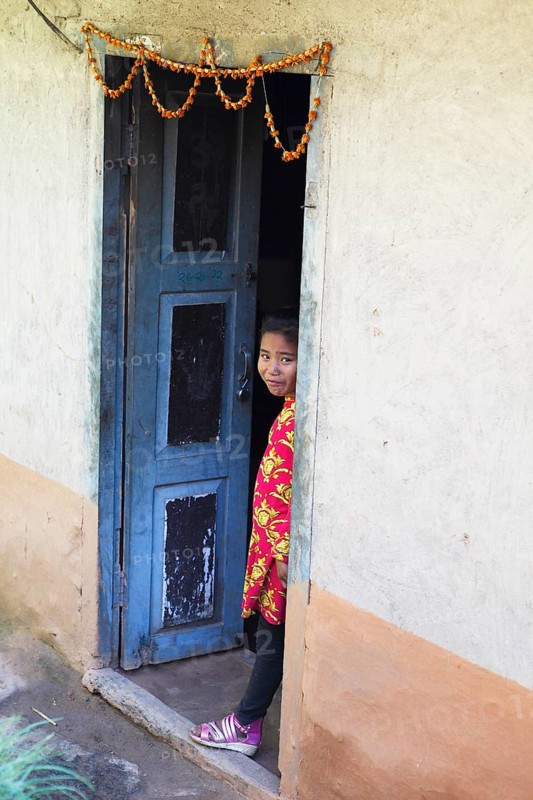 Nepalese girl looking out of a door frame