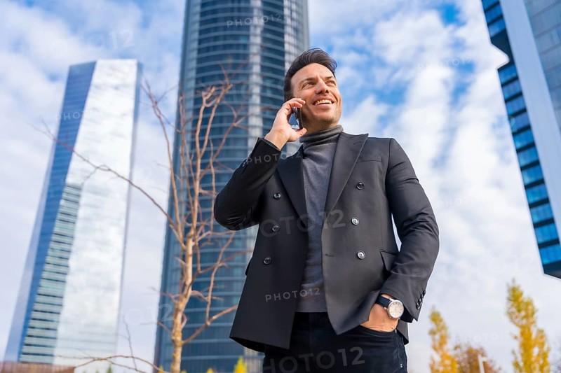 Corporate portrait of middle-aged businessman talking on the phone next to skyscraper office