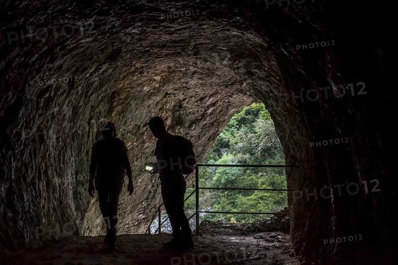 Two walkers with torch entering tunnel on the Sentier Martel path in the Gorges du Verdon