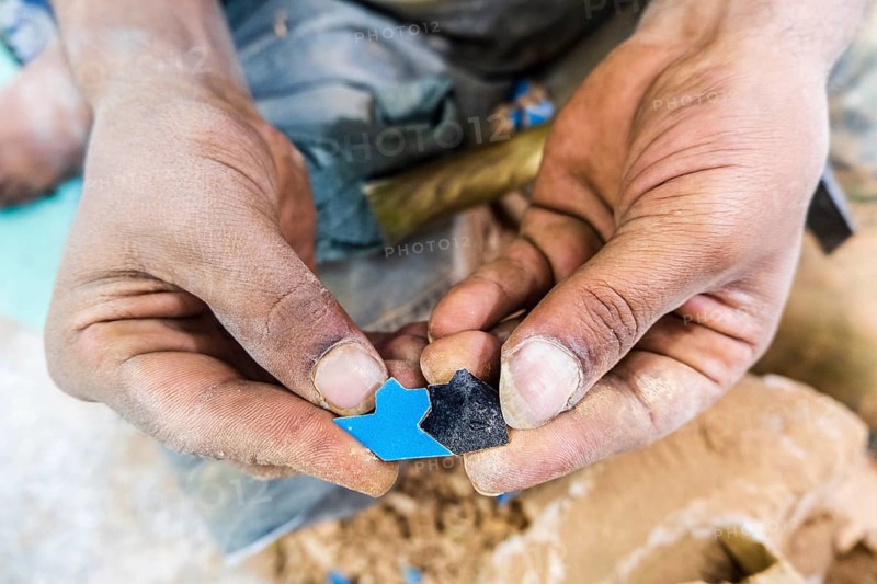 Craftsman showing hand made tiny ceramic tiles that perfectly fit each other in pottery factory in Fez
