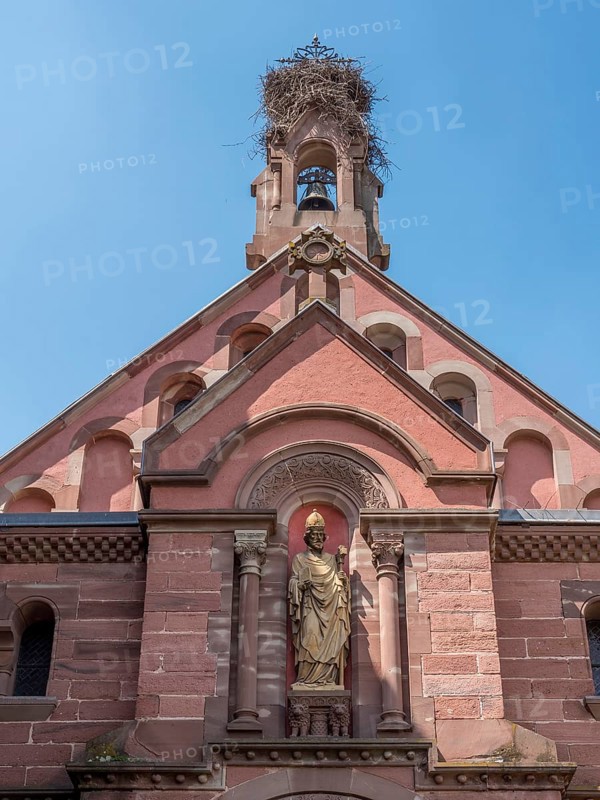 The roof section of the neo-Romanesque Byzantine St. Leo Chapel with a stork's nest on the bell tower and a sculpture on the wall