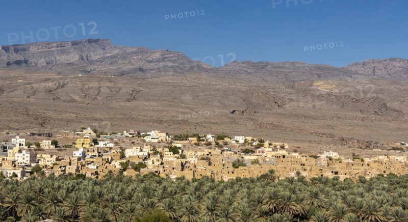 Abandoned ghost town of Al Hamra with Hajar Mountains in the background