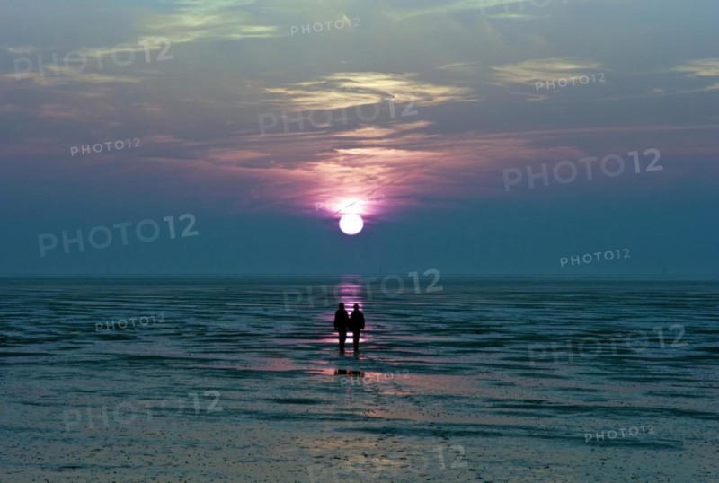 Two people at sunset in the Wadden Sea in Dorum Neufeld
