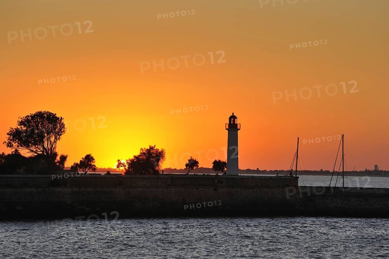 Silhouette of lighthouse at sunset in the harbour at Saint-Martin-de-Re on the island Ile de Re