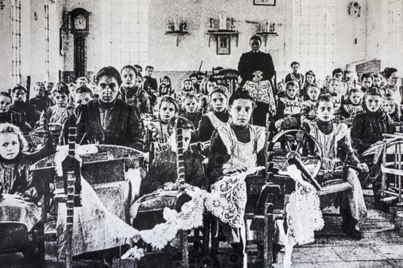 Old archival picture of school children posing in lacemaking class in early twentieth Flanders