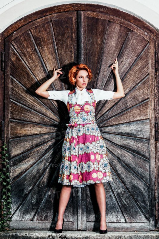 Portrait of a woman in dirndl in front of a wooden wall