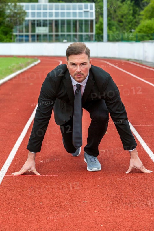 Man in a suit on a running track in starting position