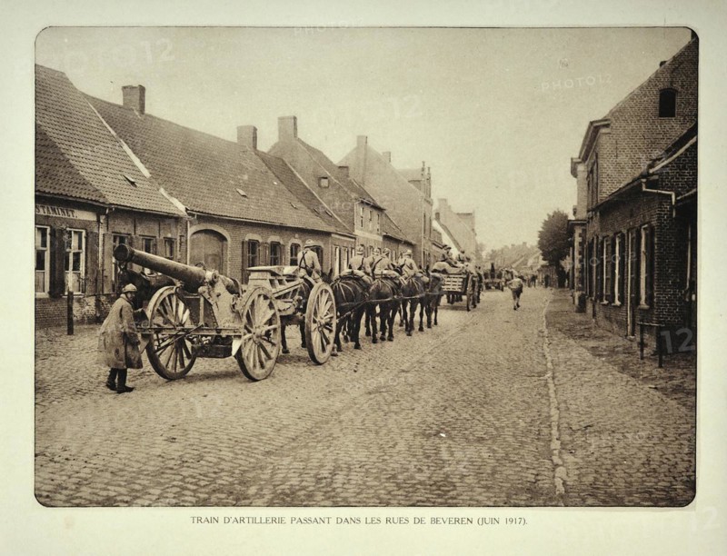 Artillery soldiers transporting cannons by horse through the village Beveren in Flanders during the First World War