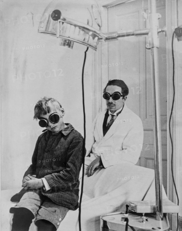 1930 photograph showing doctor and child patient with goggles during light therapy
