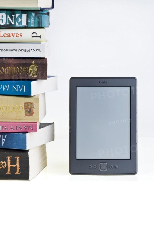Kindle e reader with a large pile of books
