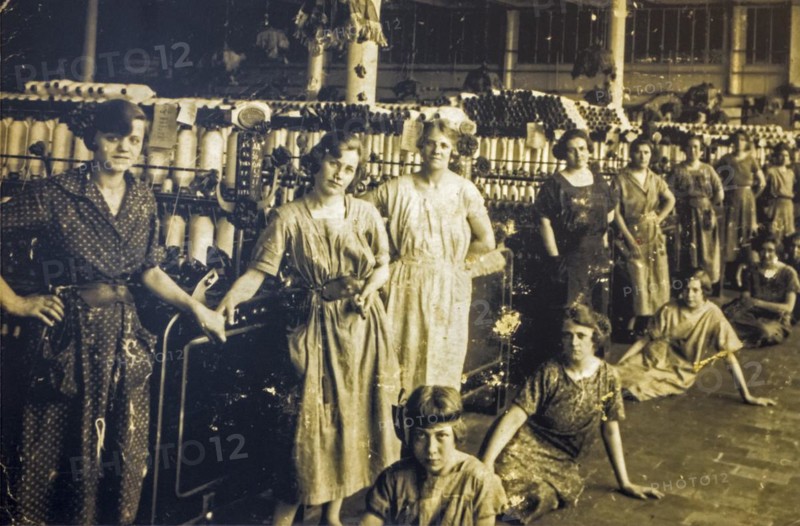 Old archival photograph showing female workers posing in spinning mill in the early twentieth century