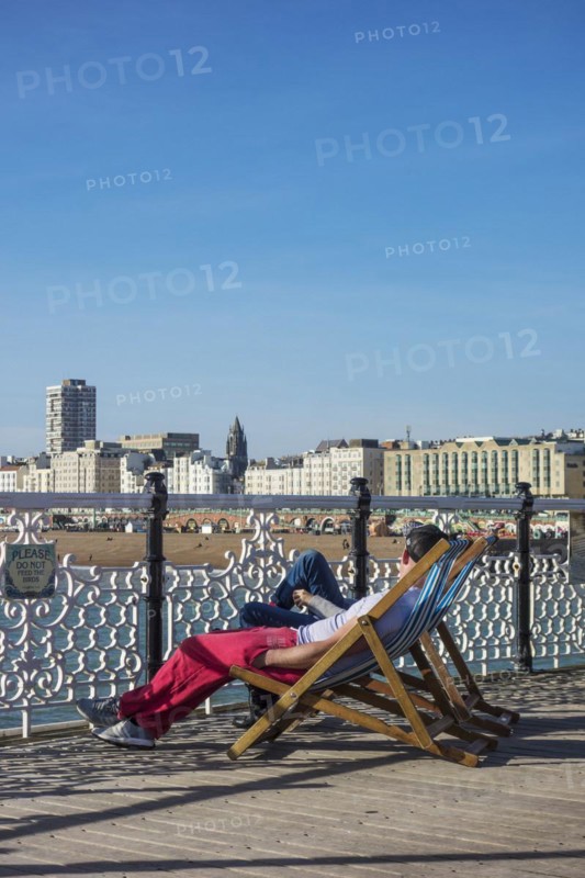 Tourists sitting on deckchairs on Brighton pier