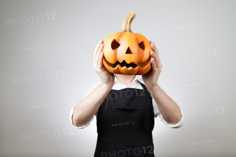 Man with apron holds a clay pumpkin in front of his head | MR:yes ph_halloween_mr