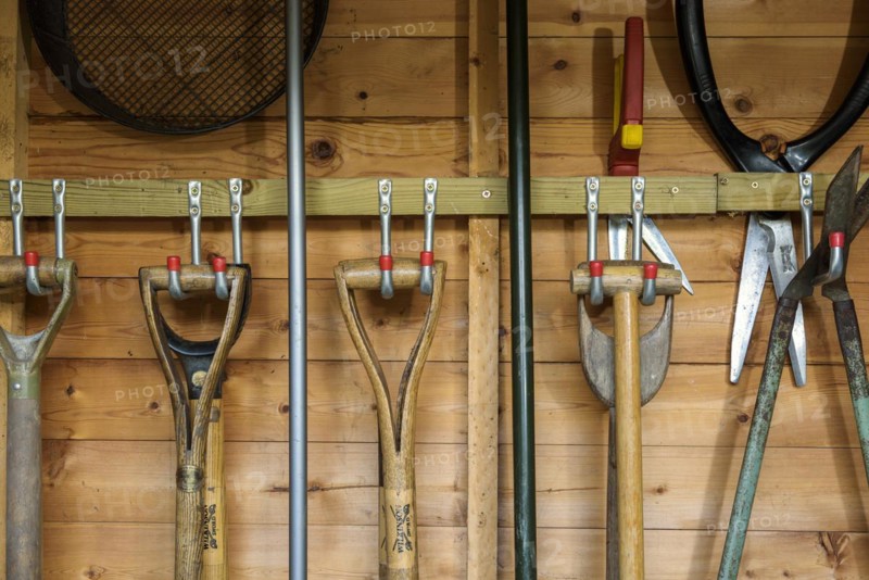 Garden tools hanging in a wooden shed