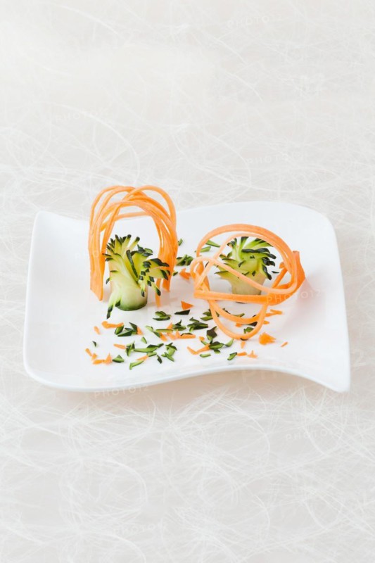 White plate decorated with carving of yellow beetroot and courgette
