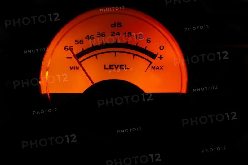 Decibel meter of a sound amplifier illuminated orange on black background