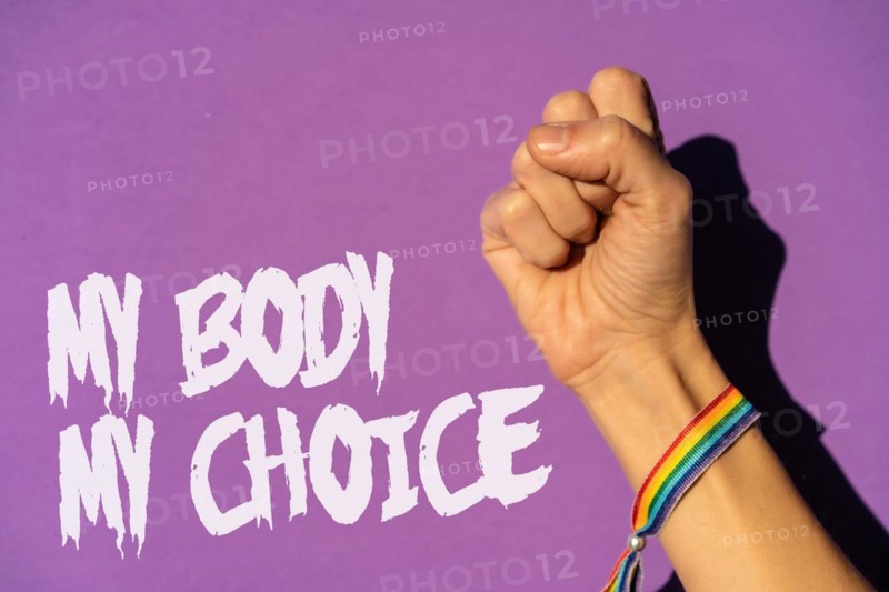 A woman with her fist raised and a text in favor of the legalization of abortion