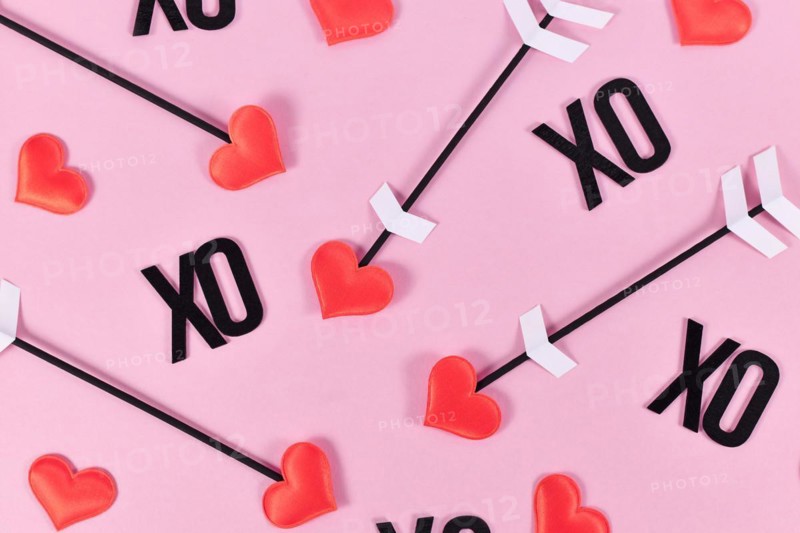 Valentine's day flat lay with cupid's love arrows and text XO on pink background