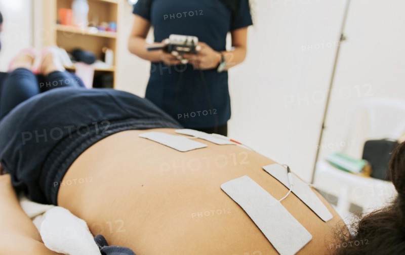 Physiotherapist electrostimulating a patient