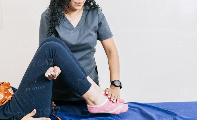 Professional physiotherapist assisting patient in leg rehabilitation