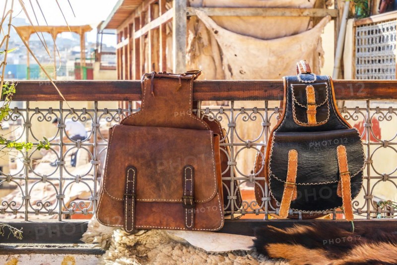 Two leather backpacks exposed for sale on terrace with a tannery view in Fes