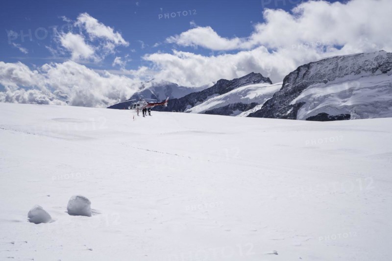 Red and white Swiss helicopter stands on Aletsch Glacier below the Jungfrau Joch
