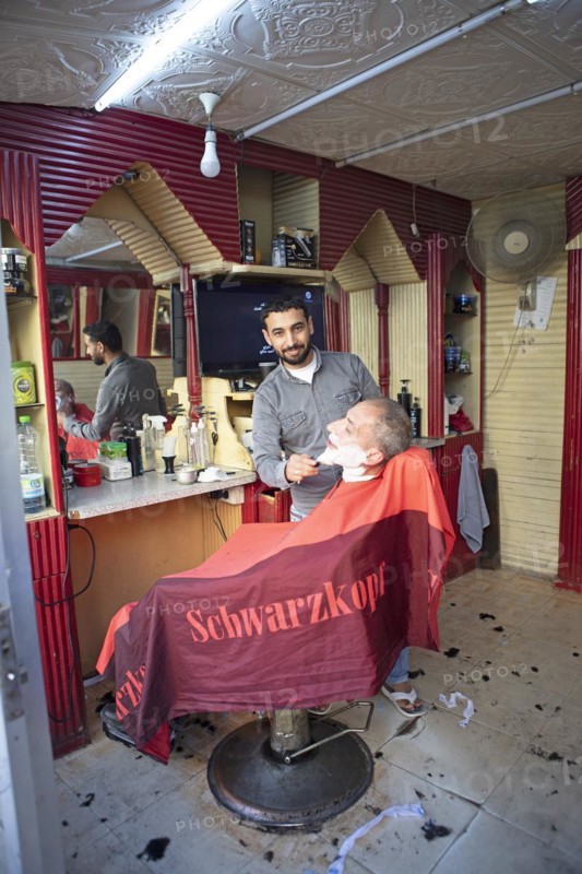 Barber shaves a customer in his shop