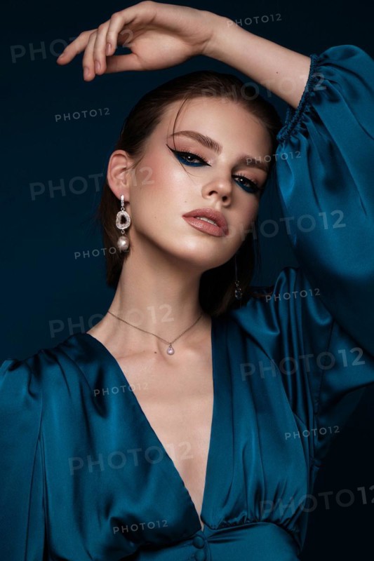Beautiful woman with blue fabric and classic arrows art make-up