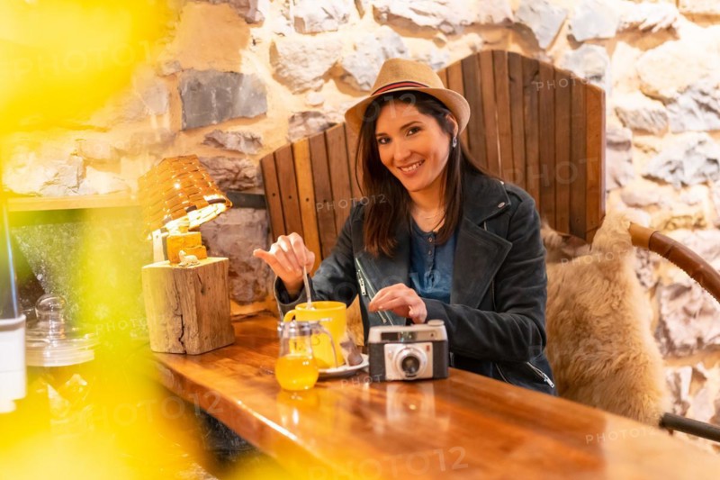 A pretty tourist with a hat and a photo camera having a cup of tea in a cafe