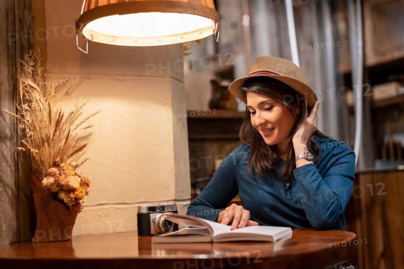 A pretty tourist with a hat and with a photo camera drinking tea in a cafe