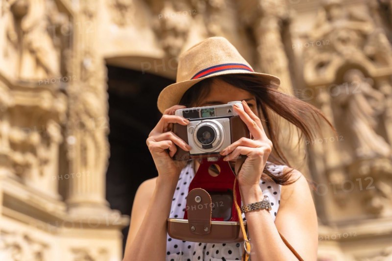 Pretty tourist in hat visiting church with photo camera