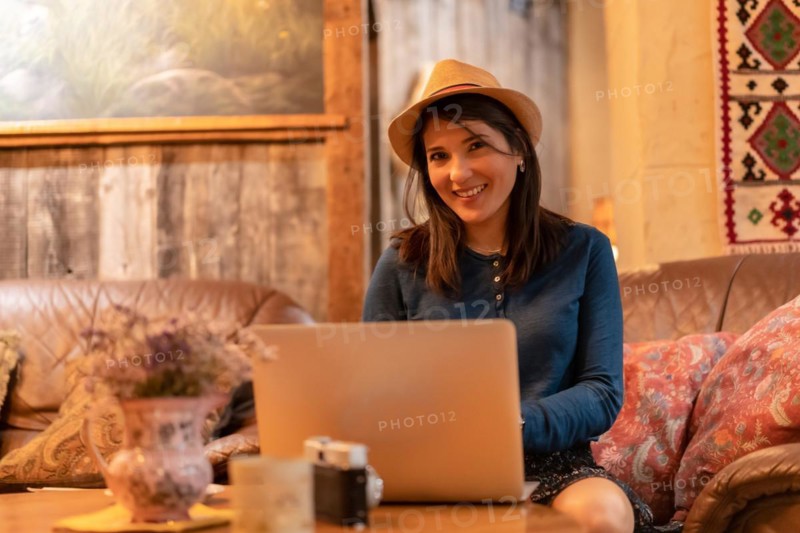 A pretty tourist in a hat and with a photo camera drinking tea in a cafeteria