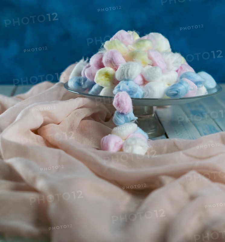 Colored cotton balls in various containers on a blue background
