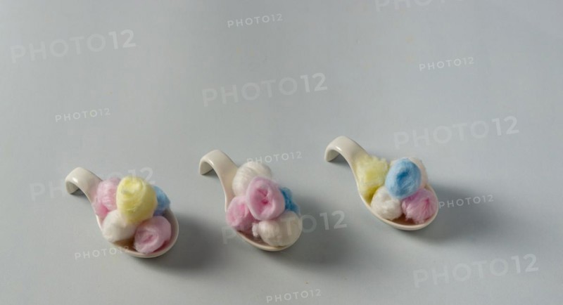 Colored cotton balls in various containers on a blue background