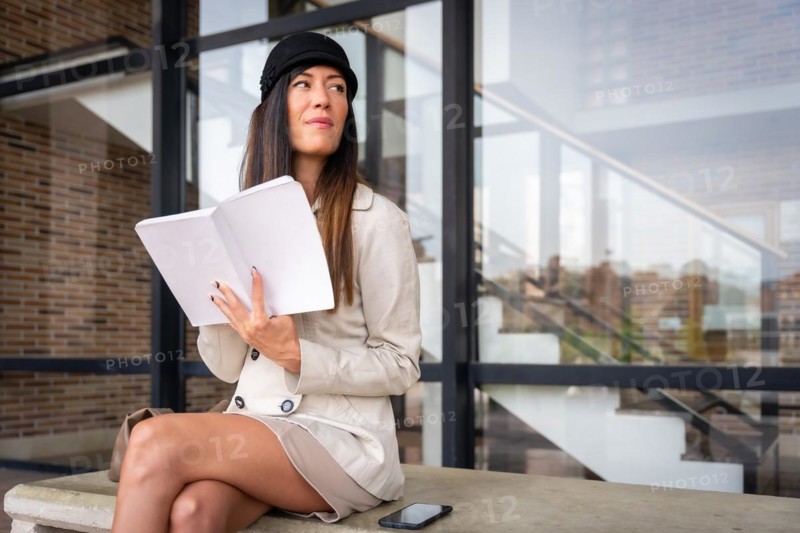 Businesswoman writing in work planner sitting in the city