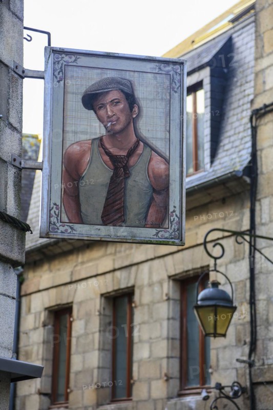 Sign of a clothing shop with portrait of young man in vest with tie