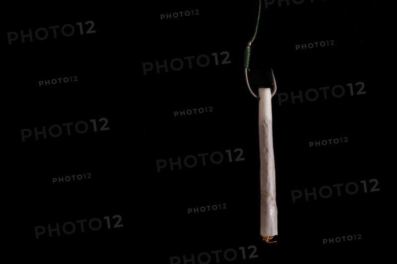 Marijuana cigarette hanging from a hook drug addiction concept close-up isolated on black background