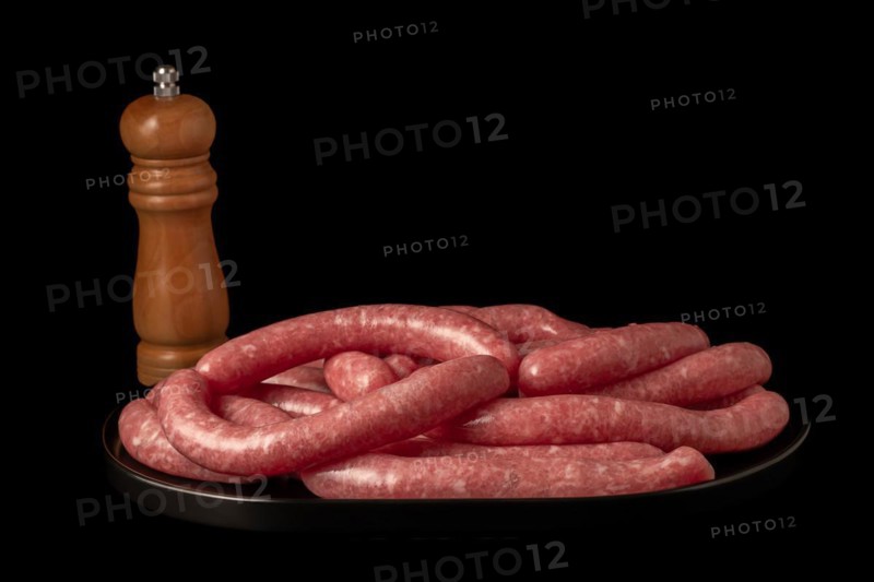 Homemade meat sausages with pepper shaker isolated on black background and copy space