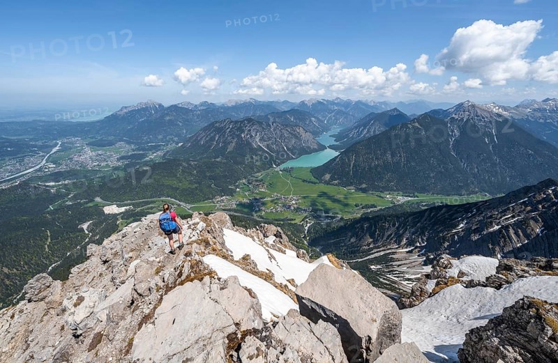 Hiker looking down from Thaneller to Plansee and eastern Lechtal Alps