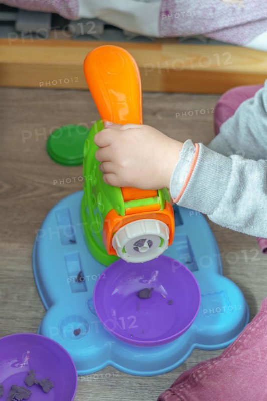 Unrecognizable child playing with a plasticine toy on the floor of his bedroom