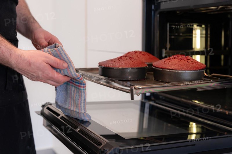 A man baker bakes a red velvet cake at home