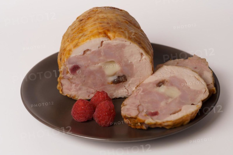 Close-up of a chicken stuffed with raspberry and goat cheese with a bowl of raspberry sauce isolated on white background