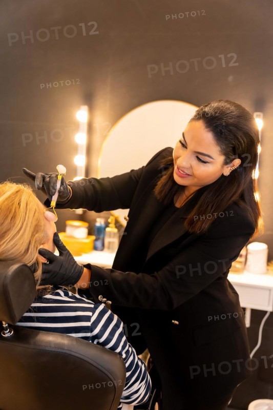 Latin ethnic woman in a beauty shop working with the client's eyebrows